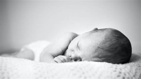 két hónapos baba békésen alszik a kiságyában