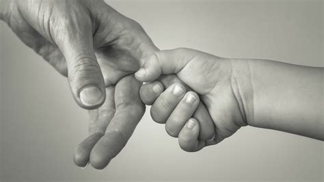 Szülő bébiőrrel a kezében, mosolyogva néz a gyermekére.