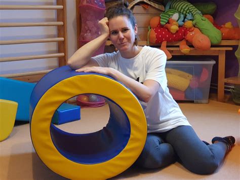 Egy gyógypedagógus egy kisgyermekkel játszik egy fejlesztő szobában, színes játékokkal
