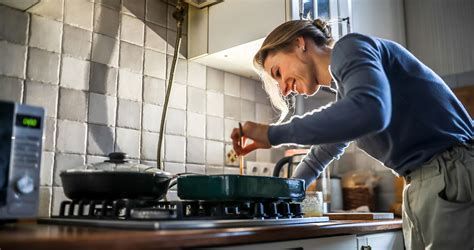 Mosolygó férfi, aki kötényben főz a konyhában