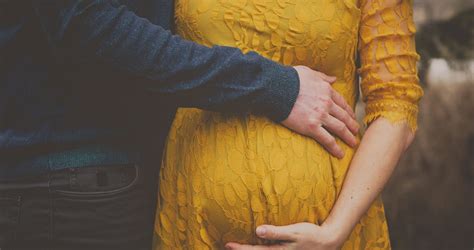 Terhes pár gyengéden öleli egymást, kifejezve szeretetüket és intimitásukat