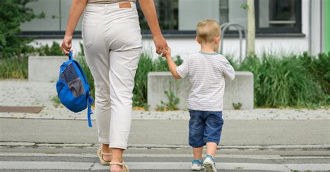 Zokogó kisgyermek az óvoda bejáratánál, anyukája lábába kapaszkodva