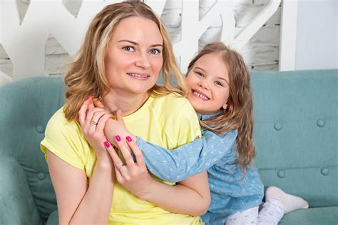 Egy pár kisbabával mosolyogva nézi egymást, egy napfényes nappaliban ülve