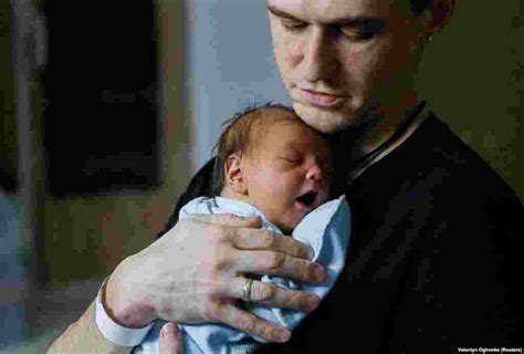 Egy édesapa újszülött gyermekét tartja a mellkasán, skin-to-skin kontaktusban.