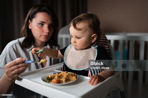 Gyermek ül az etetőszékben, boldogan eszik saját étkészletéből