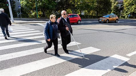 Fehér botot használó látássérült személy a forgalomban