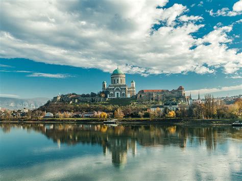 Terhes nő, aki a hasát simogatja, és a háttérben homályos orvosi rendelő látható.