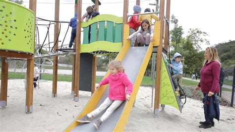 Anyukák beszélgetnek egy játszótéren, miközben gyermekeik játszanak
