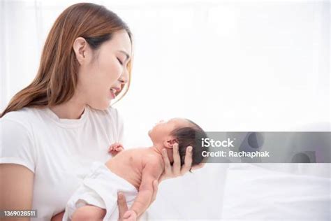 Egy fáradt, de boldog anya, aki 7 hónapos babájával játszik a padlón.